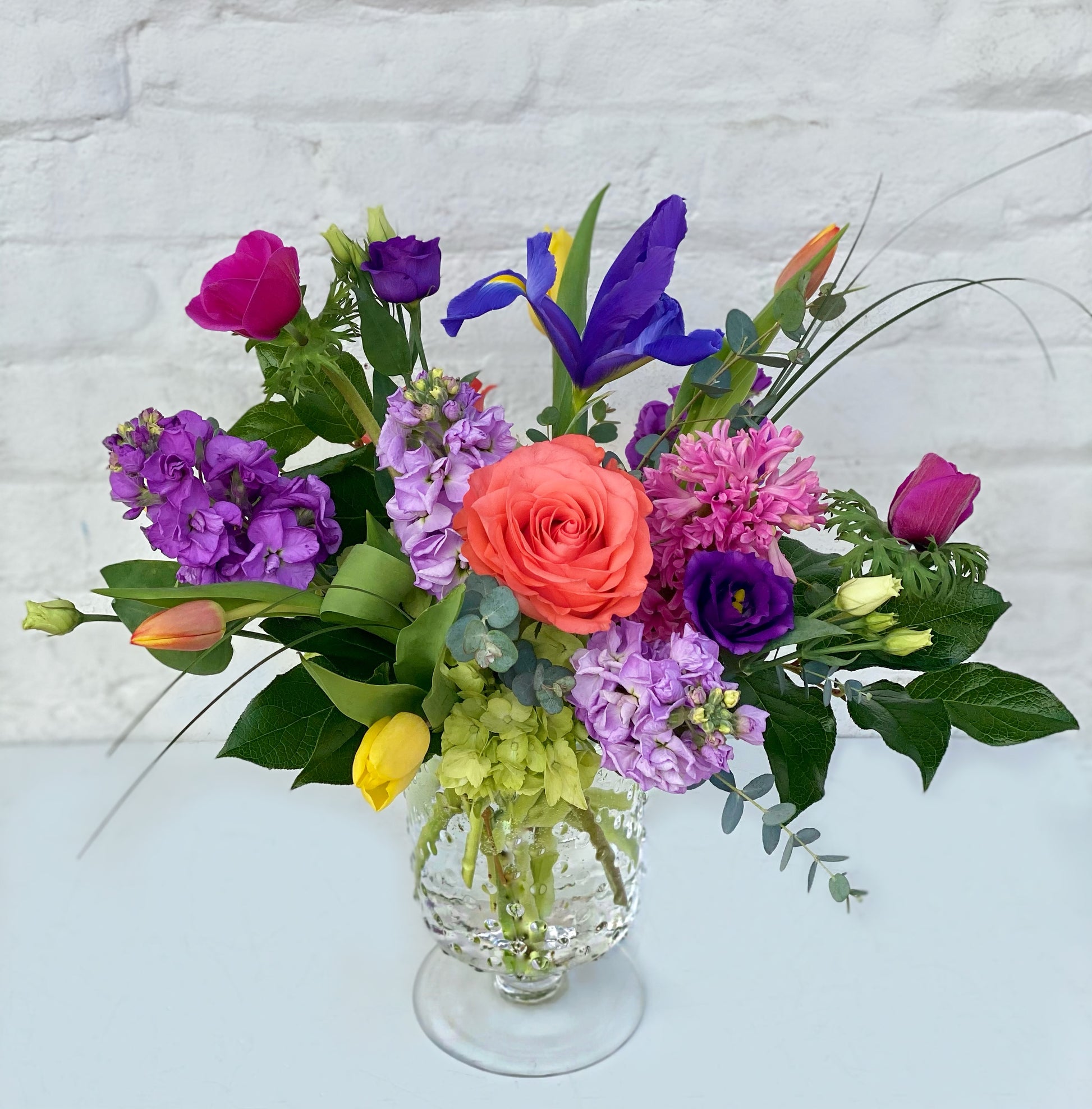 Colorful flower arrangement in a glass vase on a light background