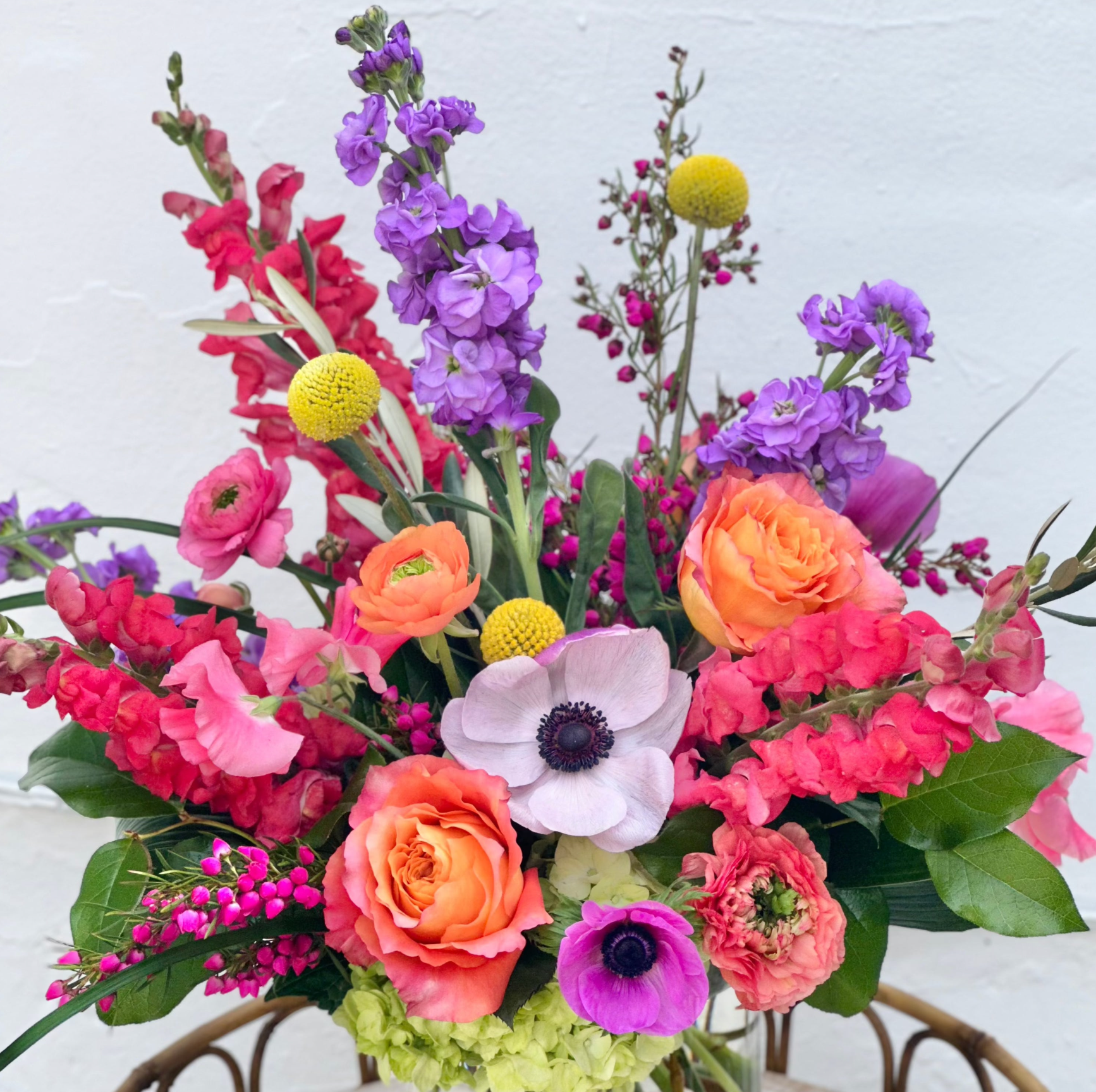Colorful bouquet of flowers with pink, orange, purple, and green colors on a white background.