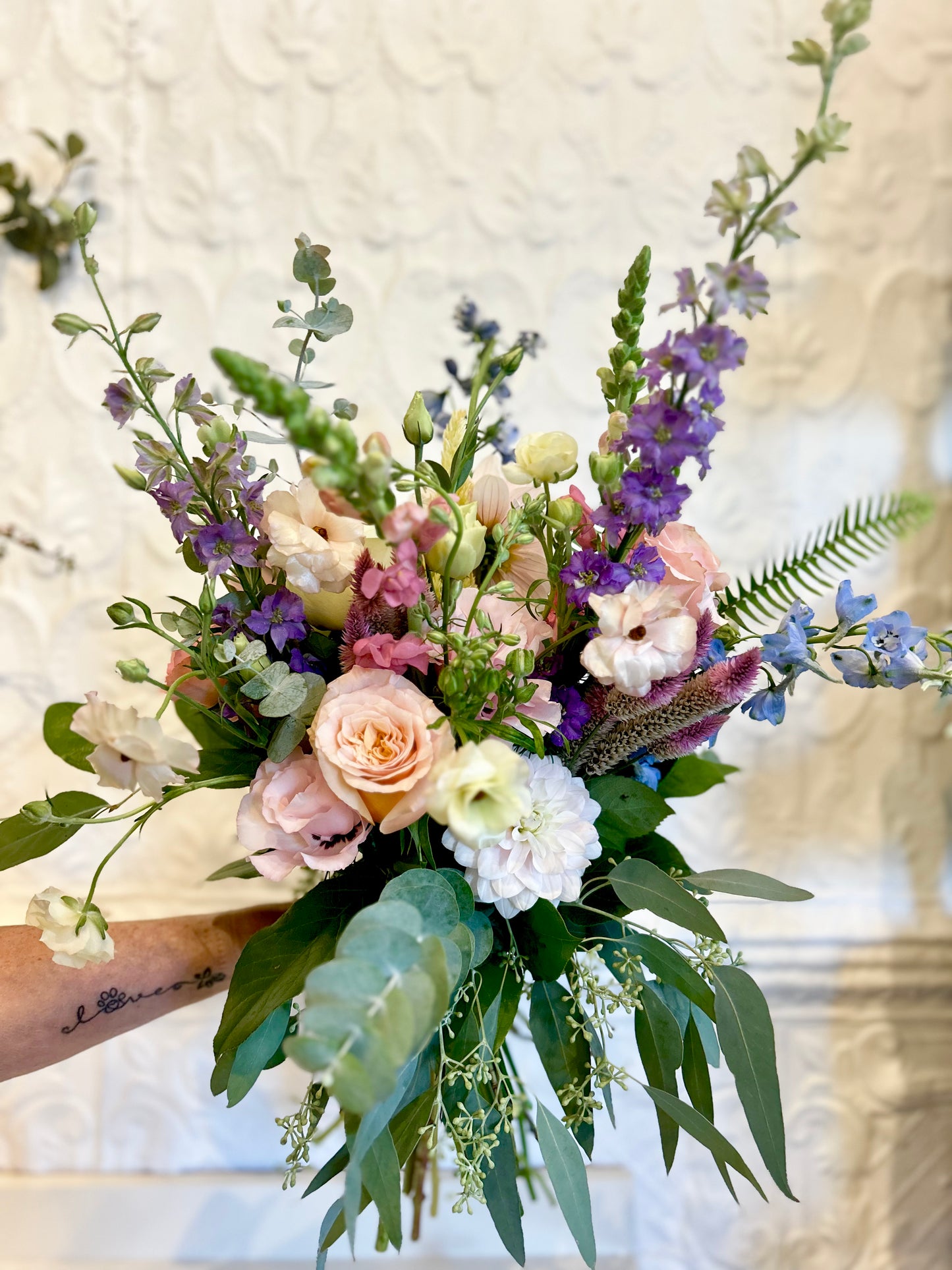 Bouquet of flowers with pastel colors and greenery on a neutral background
